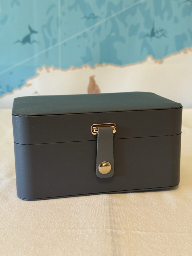 Compact travel jewelry case with multiple sections, ideal for keeping accessories organized while traveling. Hard case keeps jewelry protected.