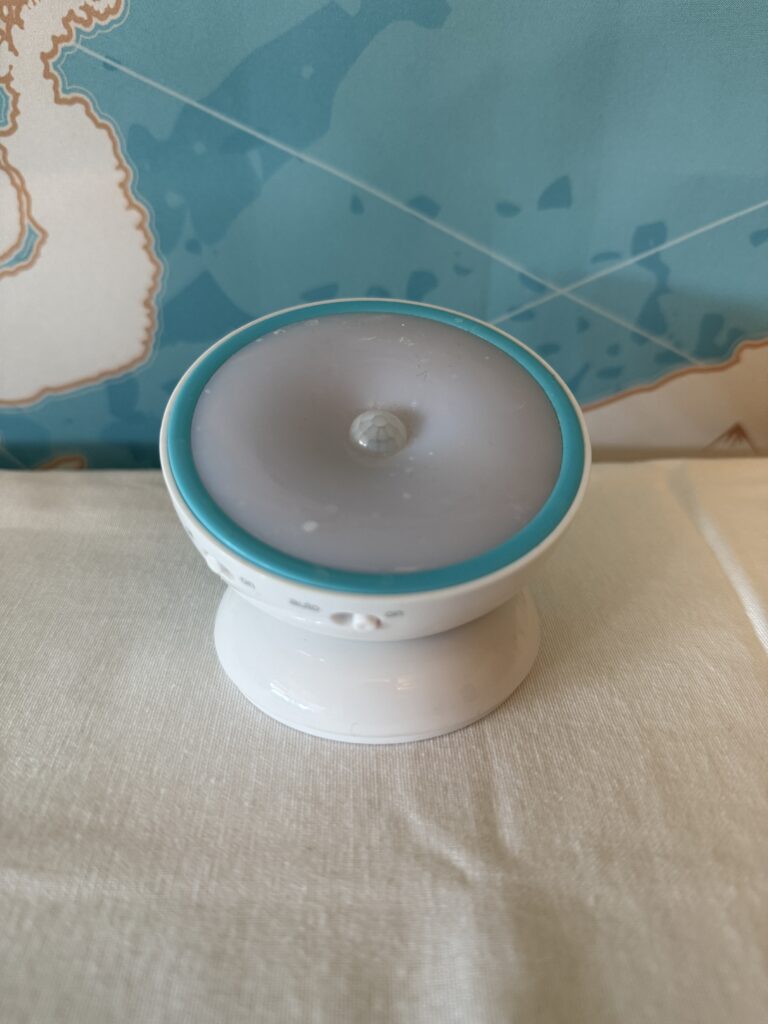 Compact motion sensor night light glowing softly in a dark room