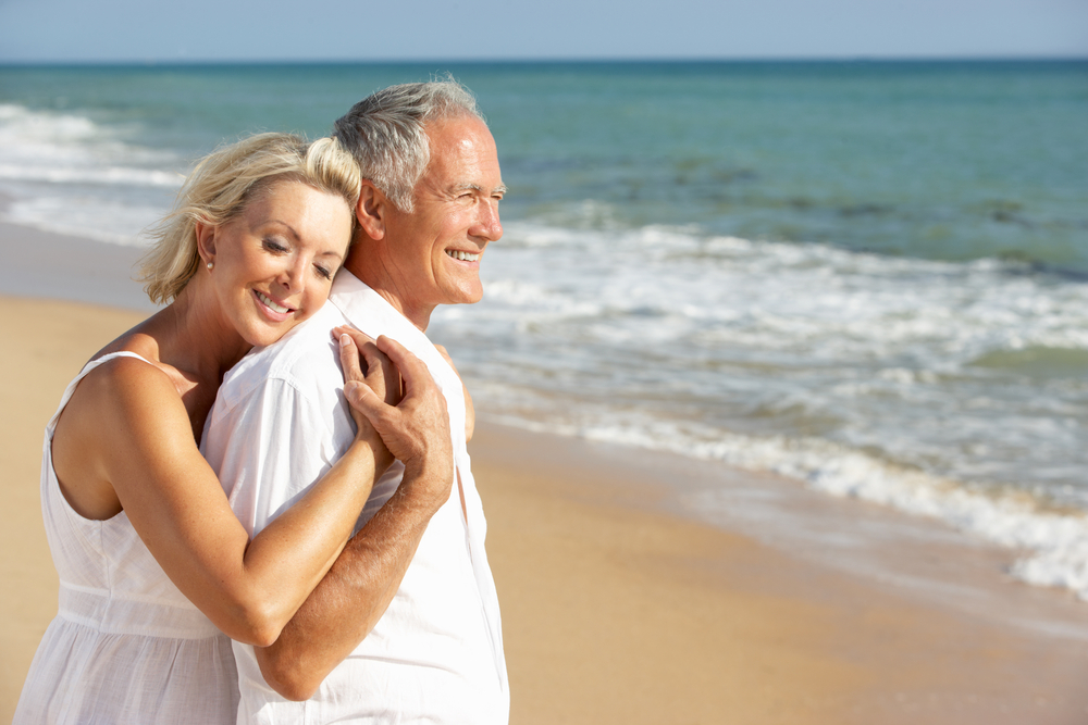 Couple dressed in white clothing smiling together on vacation.