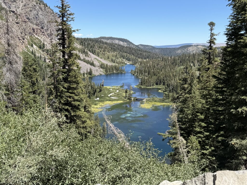 Close-up view of Twin Lakes in Mammoth Lakes, California, featuring the wooden bridge that crosses the lake, surrounded by pine trees and reflected mountain scenery.